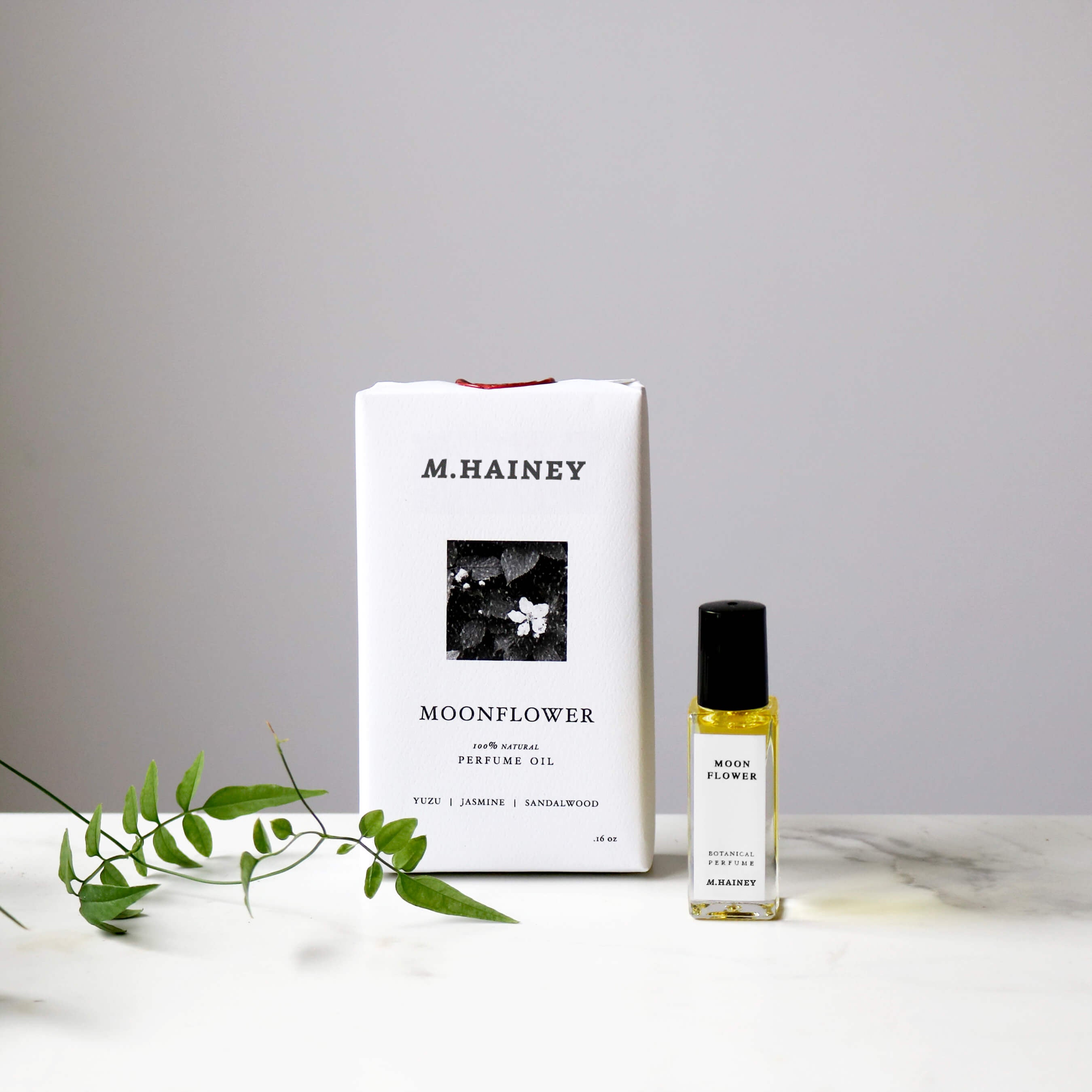 M. Hainey Moonflower perfume oil bottle and packaging on a marble surface with a gray background