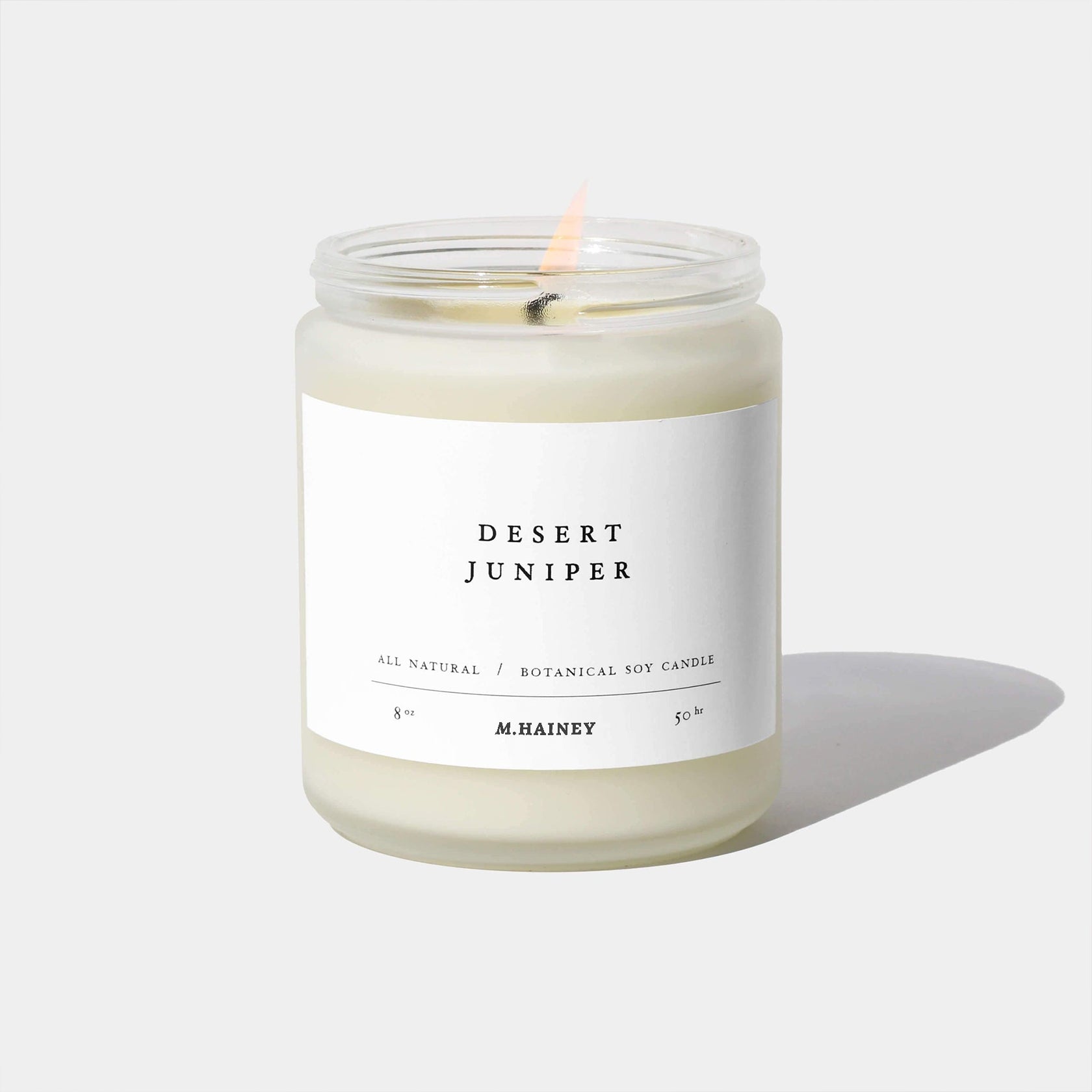 Candle in a glass jar with a white label on a light gray background