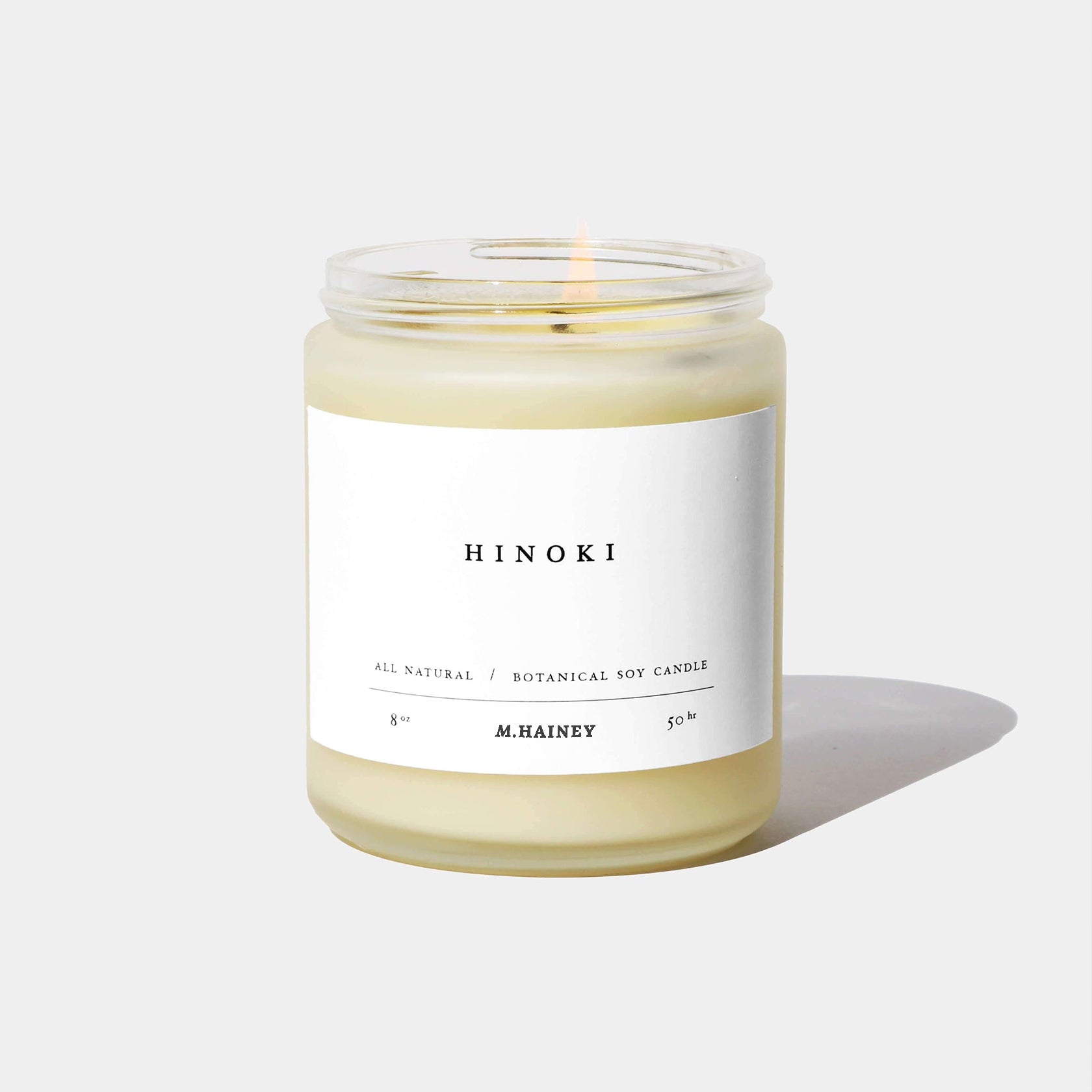 Hinoki candle in a glass jar with a white label on a light gray background