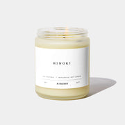 Hinoki candle in a glass jar with a white label on a light gray background