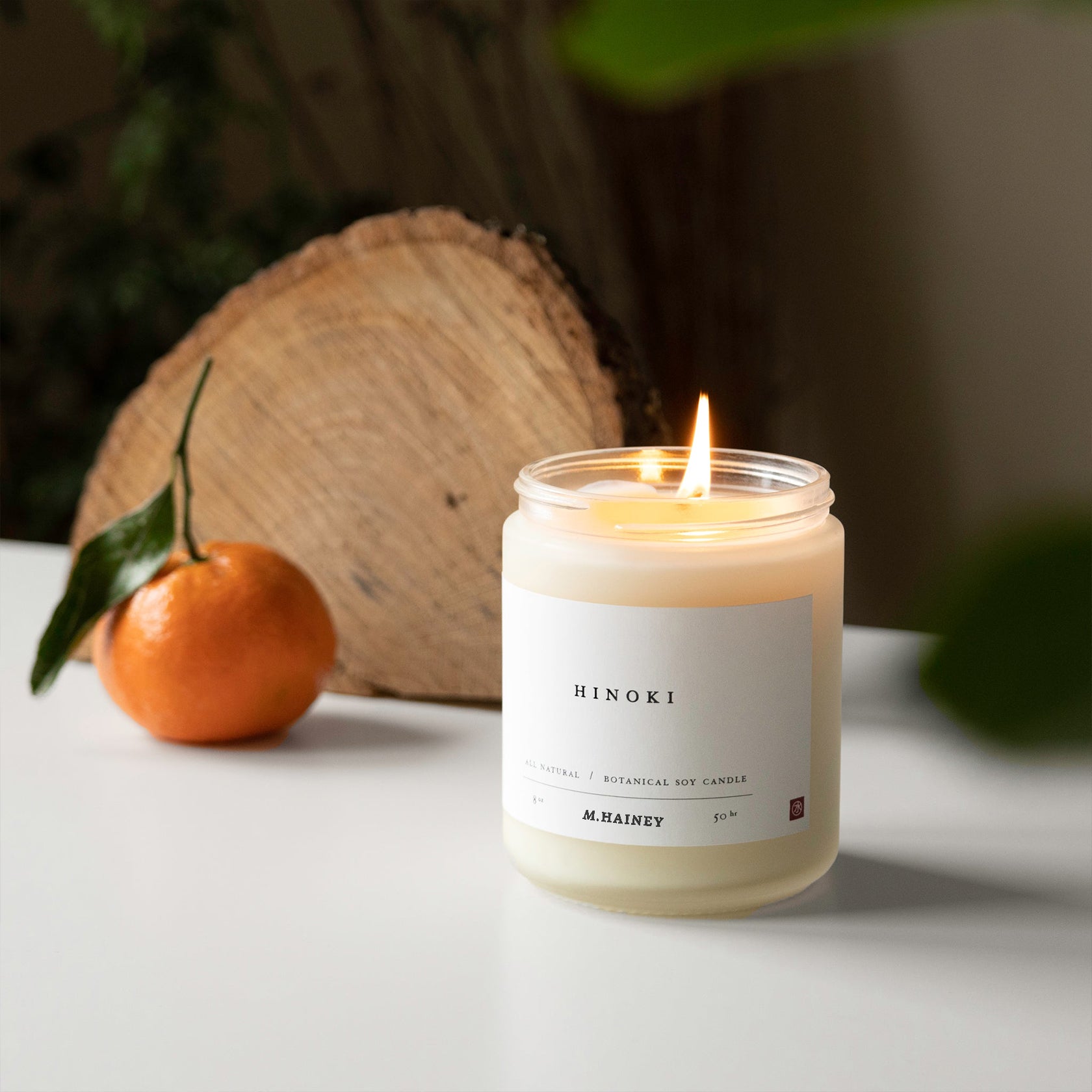 Candle labeled 'Hinoki' with an orange and wooden log in the background