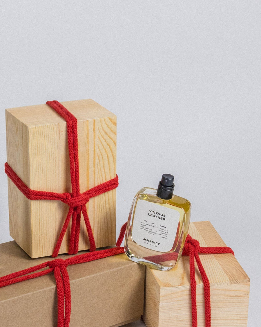 Three wooden gift boxes tied with red string and three small bottles on a light gray background