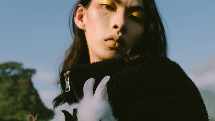Person holding a white rabbit against a natural background